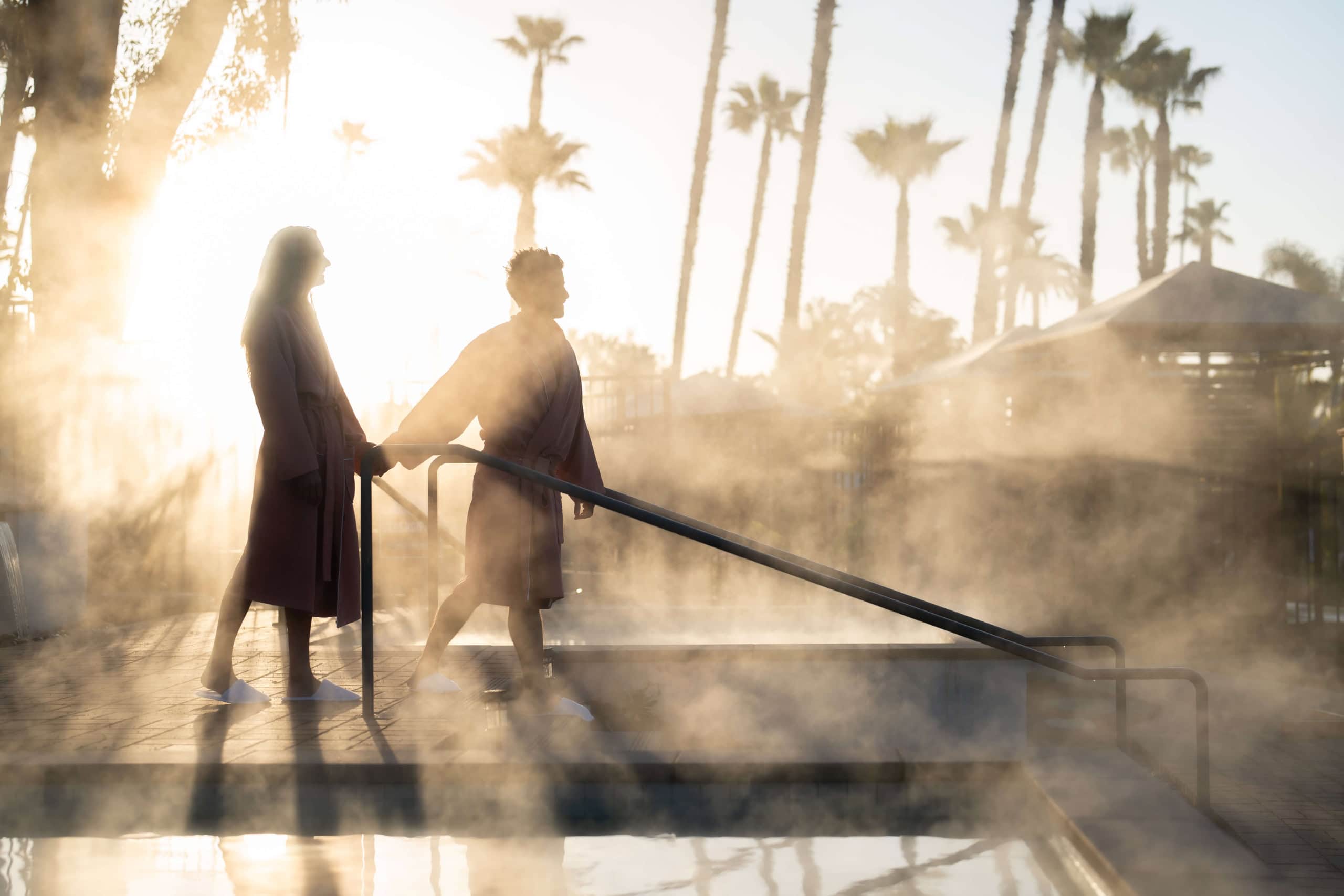 Couple at dawn walking by a steamy pool