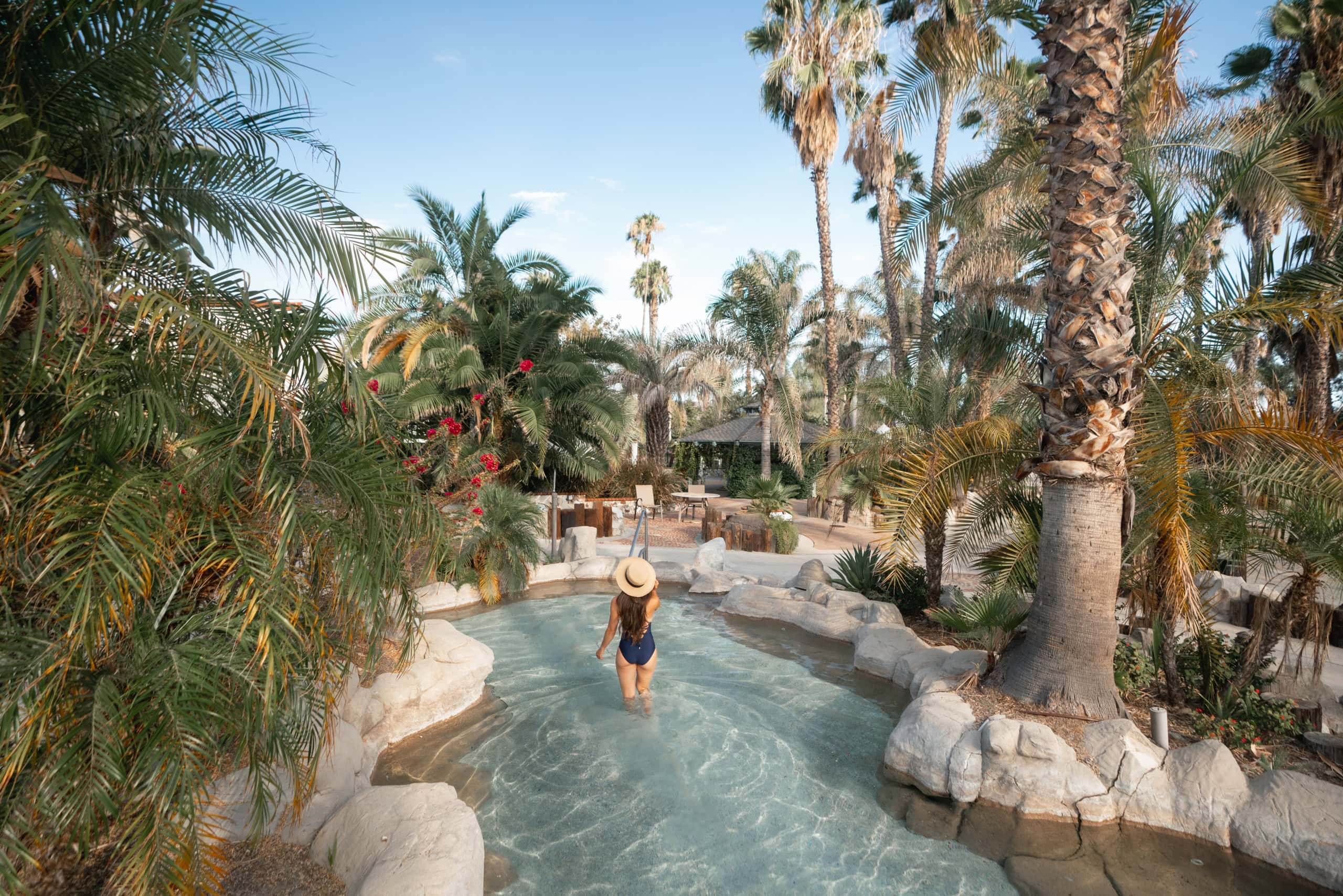 Woman enjoying a warm mineral hot spring pool surrounded by palm trees at Murrieta Hot Springs Resor.