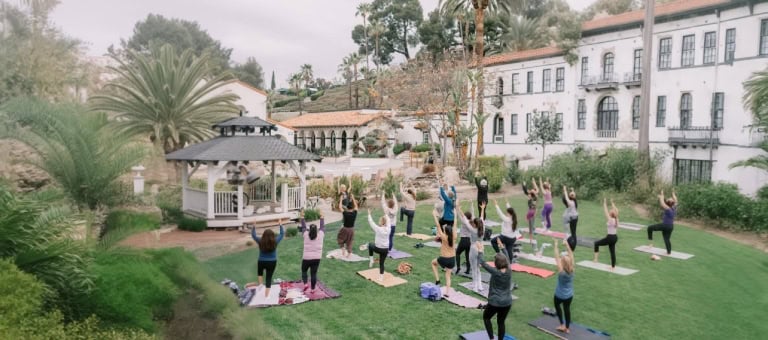 Group of people practicing yoga outdoors at Murrieta Hot Springs Resort garden.