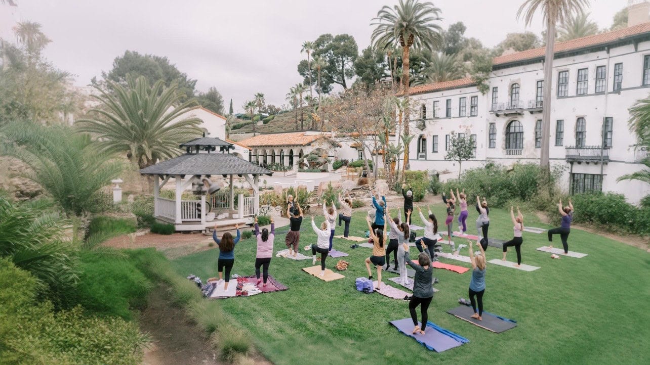 Group of people practicing yoga outdoors at Murrieta Hot Springs Resort garden.