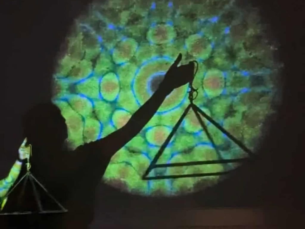 Person holding a triangle and scale symbol with colorful background at wellness event.