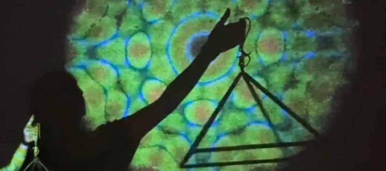 Person holding a triangle and scale symbol with colorful background at wellness event.
