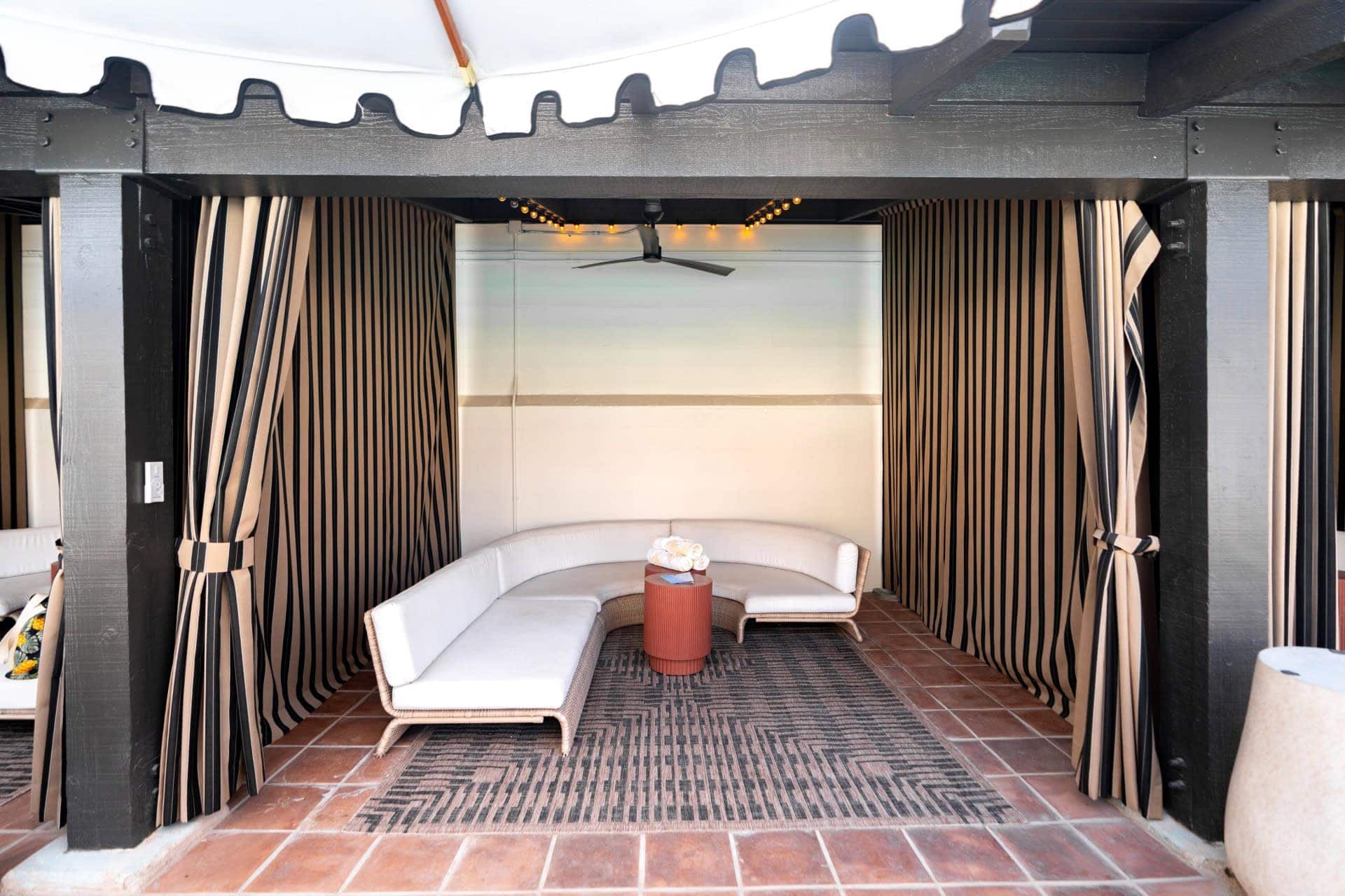 Relaxing outdoor lounge with white seating and striped curtains at Murrieta Hot Springs.